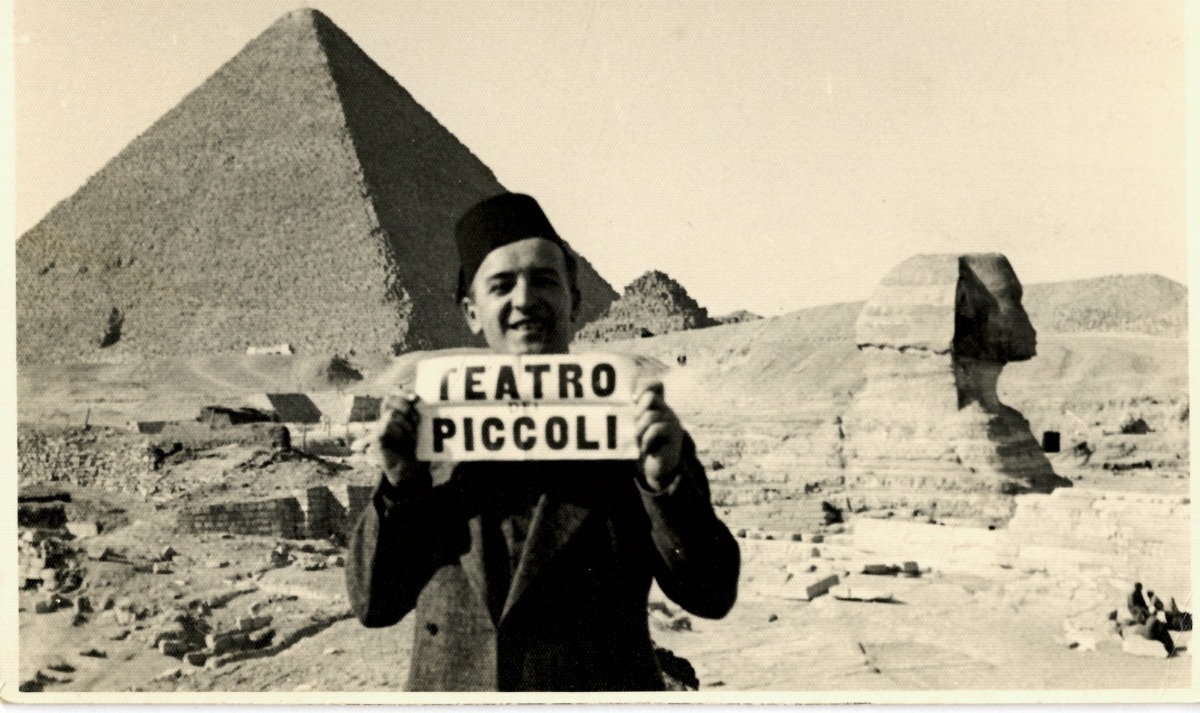 uomo che sostiene cartellone 'Teatro Piccoli' davanti a piramide