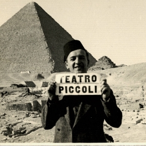uomo che sostiene cartellone 'Teatro Piccoli' davanti a piramide